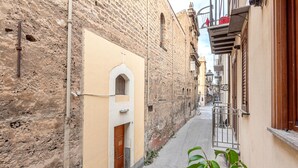 A narrow street with buildings on either side, a wooden door, and a metal gate. - Casa Dolce Vita by Wonderful Italy (Palermo)