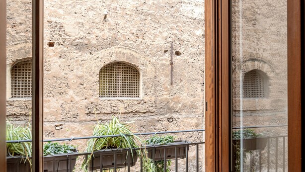 A view through a window of a building with arched windows and a stone wall. - Casa Dolce Vita by Wonderful Italy (Palermo)