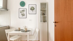A small kitchen with a white table, two chairs, a clock, and framed botanical prints on the wall. - Casa Dolce Vita by Wonderful Italy (Palermo)