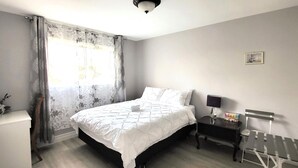 Une chambre à coucher avec un lit, une table de chevet, une lampe et un banc près de la fenêtre.
