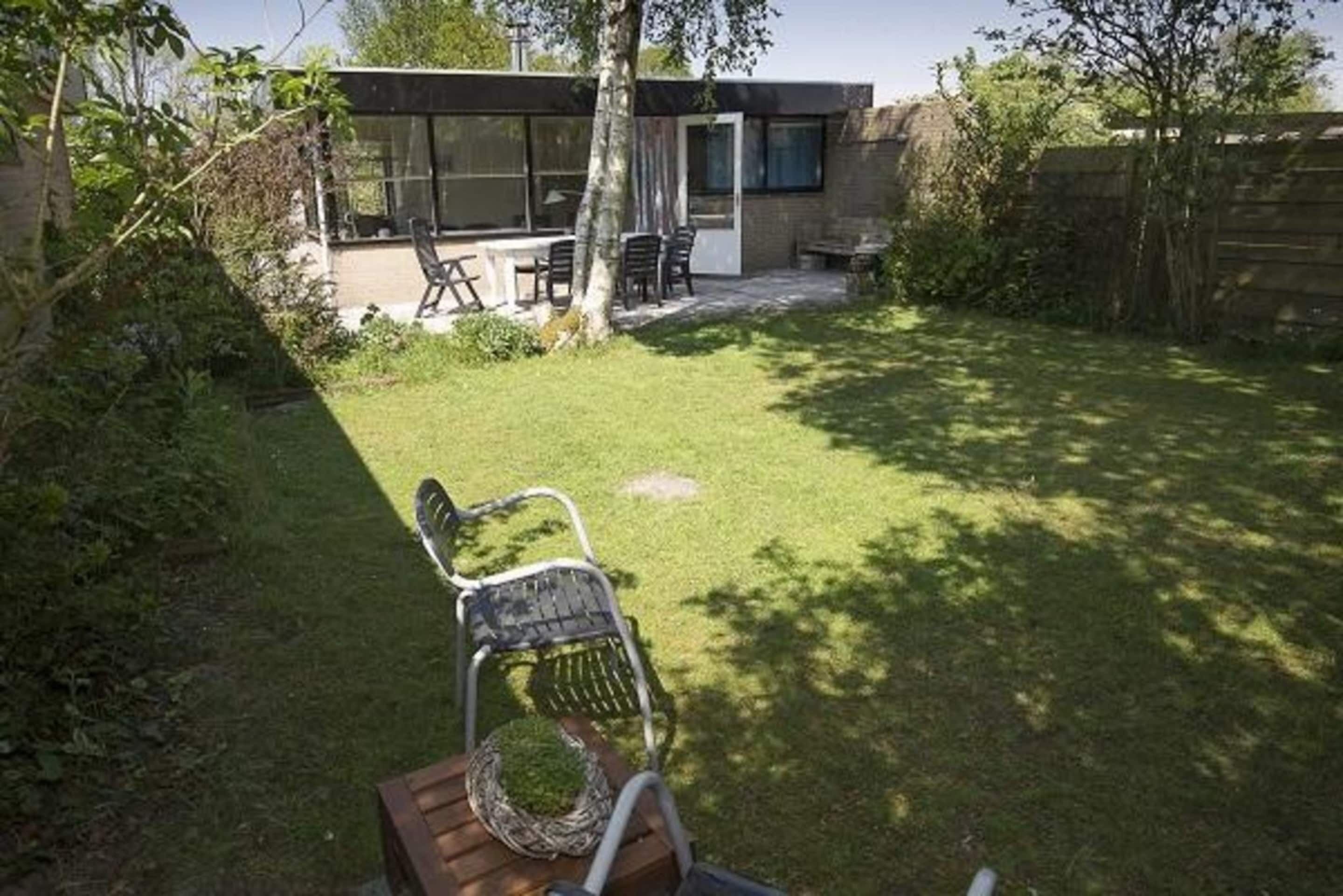 A modern house with a patio area, a wooden deck, and a lawn.
