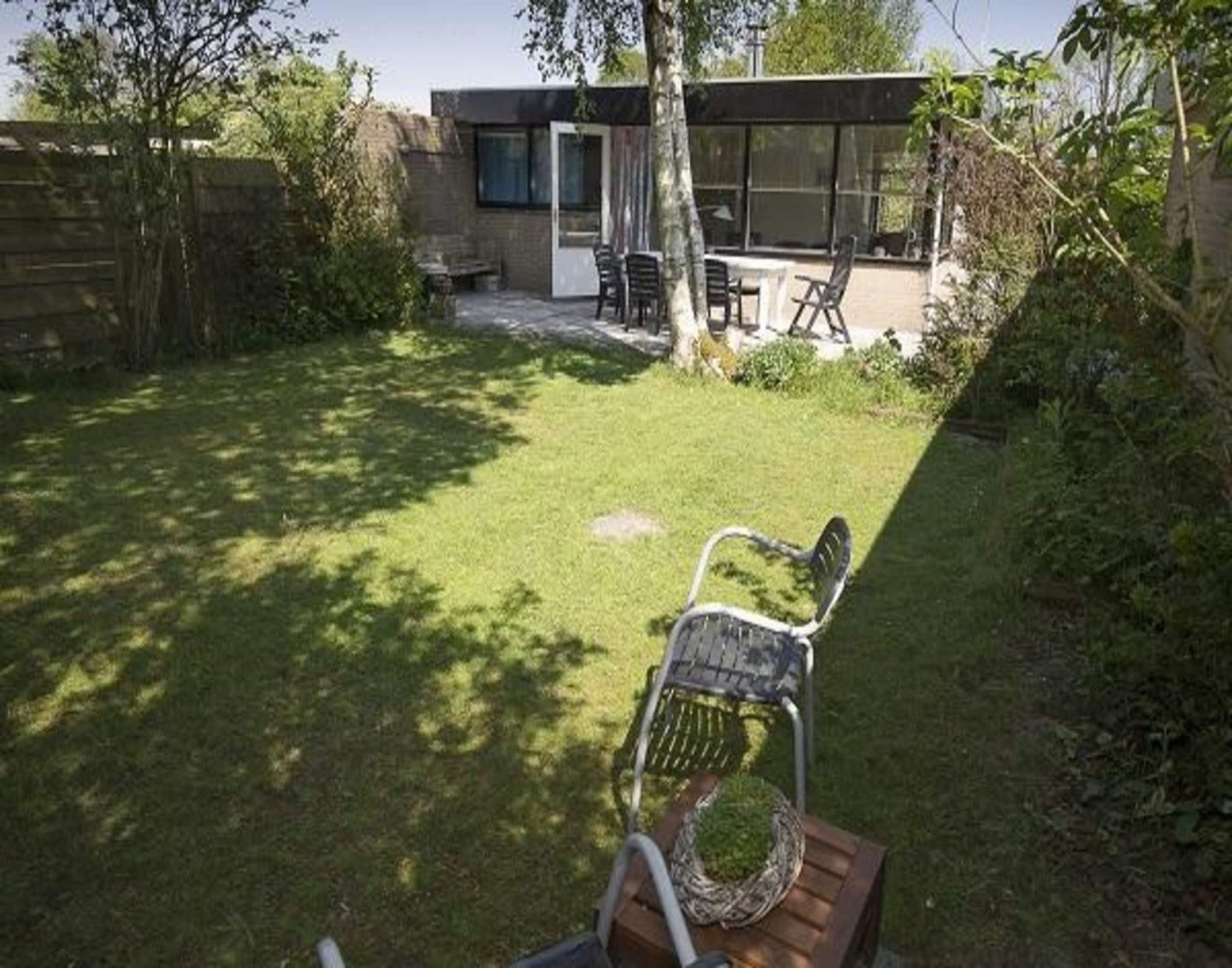 A modern house with a patio area, a wooden table, and a metal chair.