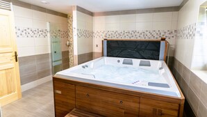 Une salle de bain moderne avec une grande baignoire en bois, une douche en verre et des murs carrelés.