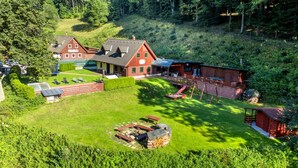 Un chalet comprenant plusieurs cabanes, un bâtiment principal et une pelouse bien entretenue, avec des espaces de détente en plein air et un foyer.