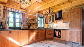 Une cuisine en bois avec un poêle noir, des placards en bois et un sol carrelé.