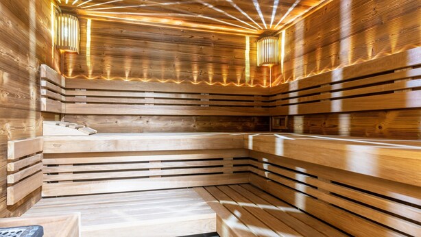Un sauna avec des bancs en bois et des parois à lattes, doté de luminaires intégrés.