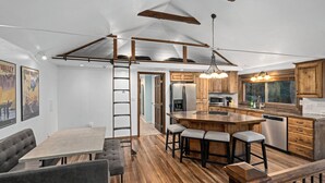 Une cuisine moderne avec des meubles en bois, un îlot central doté de tabourets et un coin repas avec une table et des bancs.