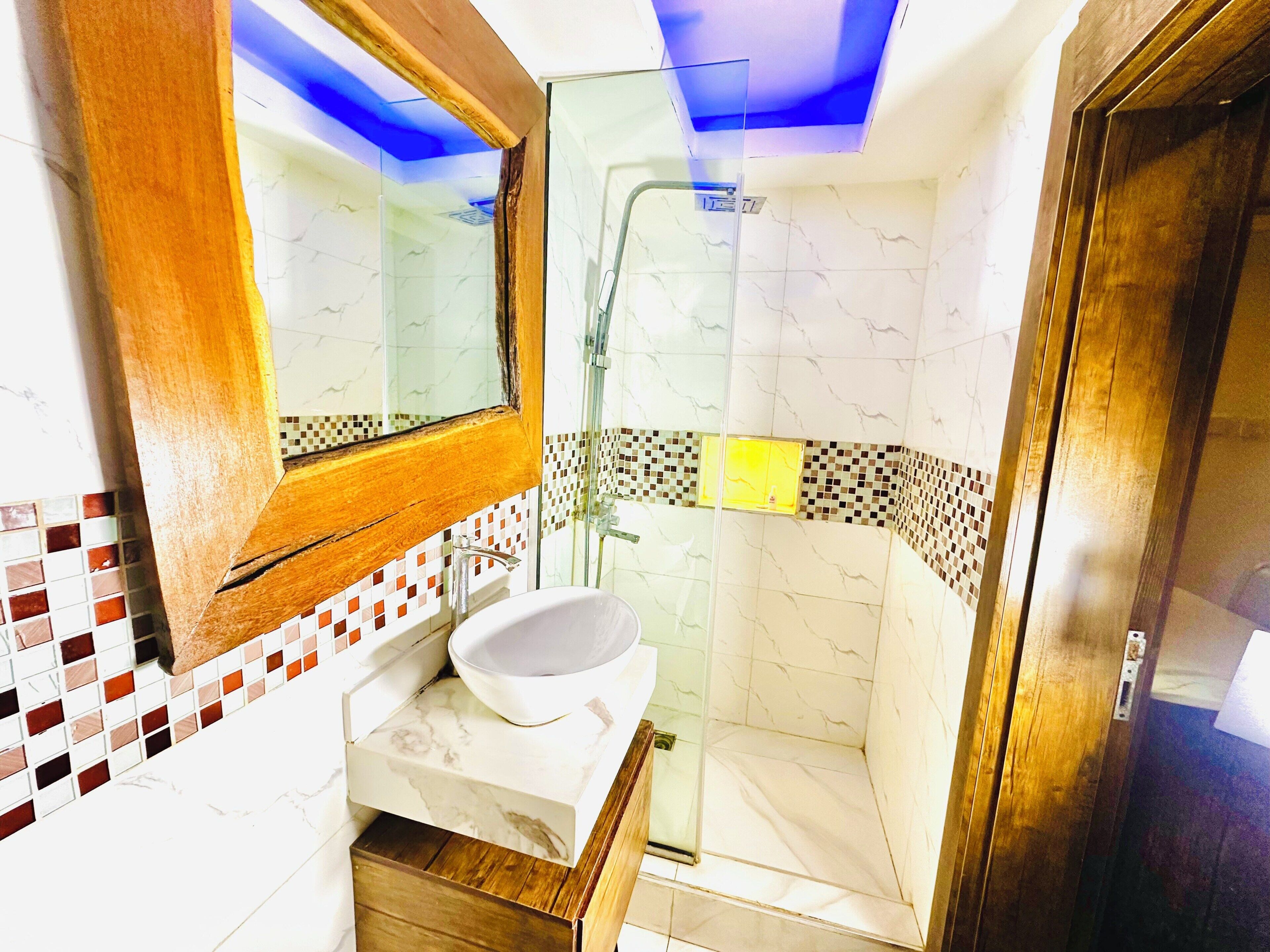 A bathroom with a white sink, a mirror, and a shower area.