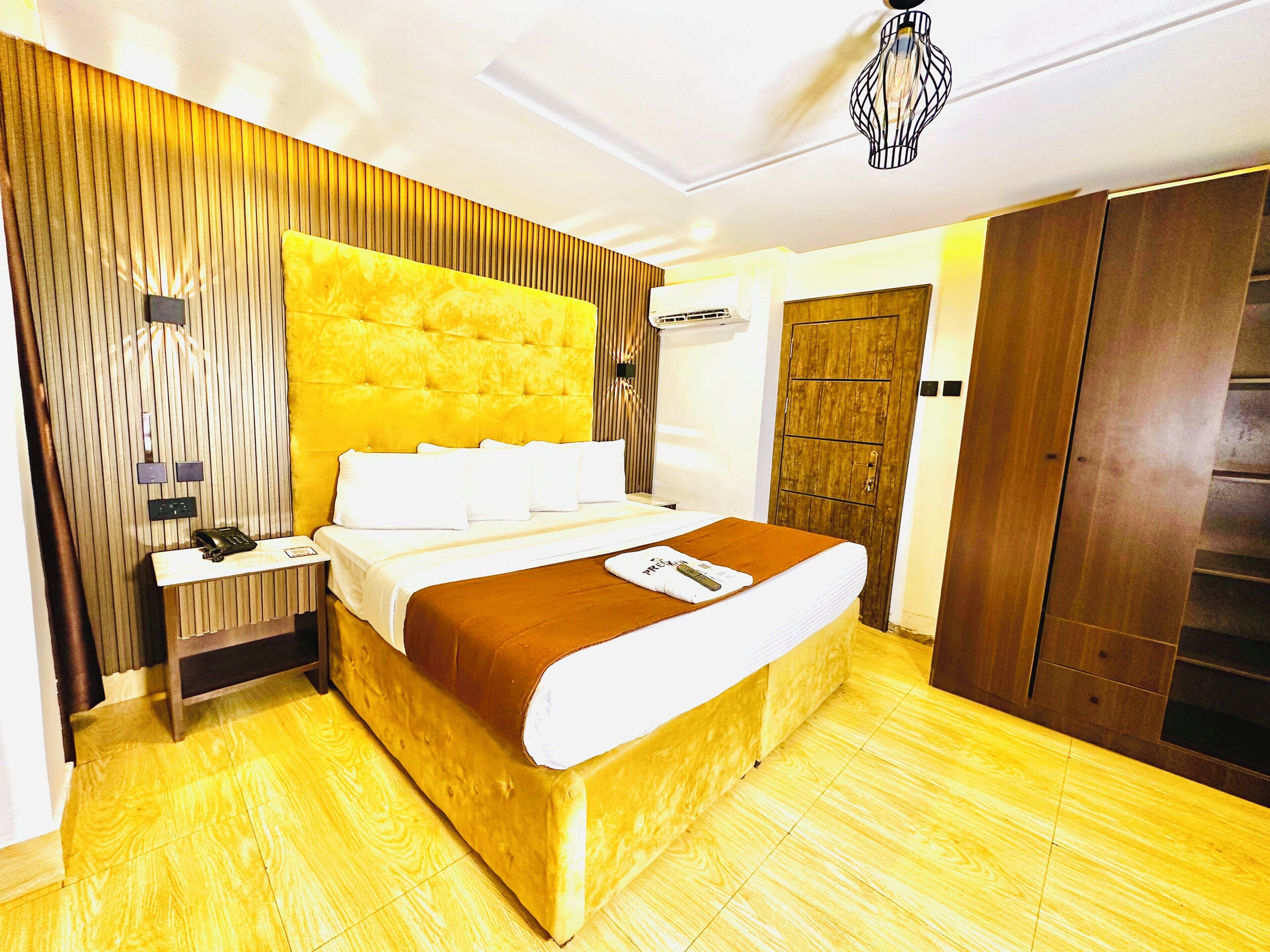 Habitación de hotel con una cama grande, una mesita de noche, un armario y una lámpara moderna.