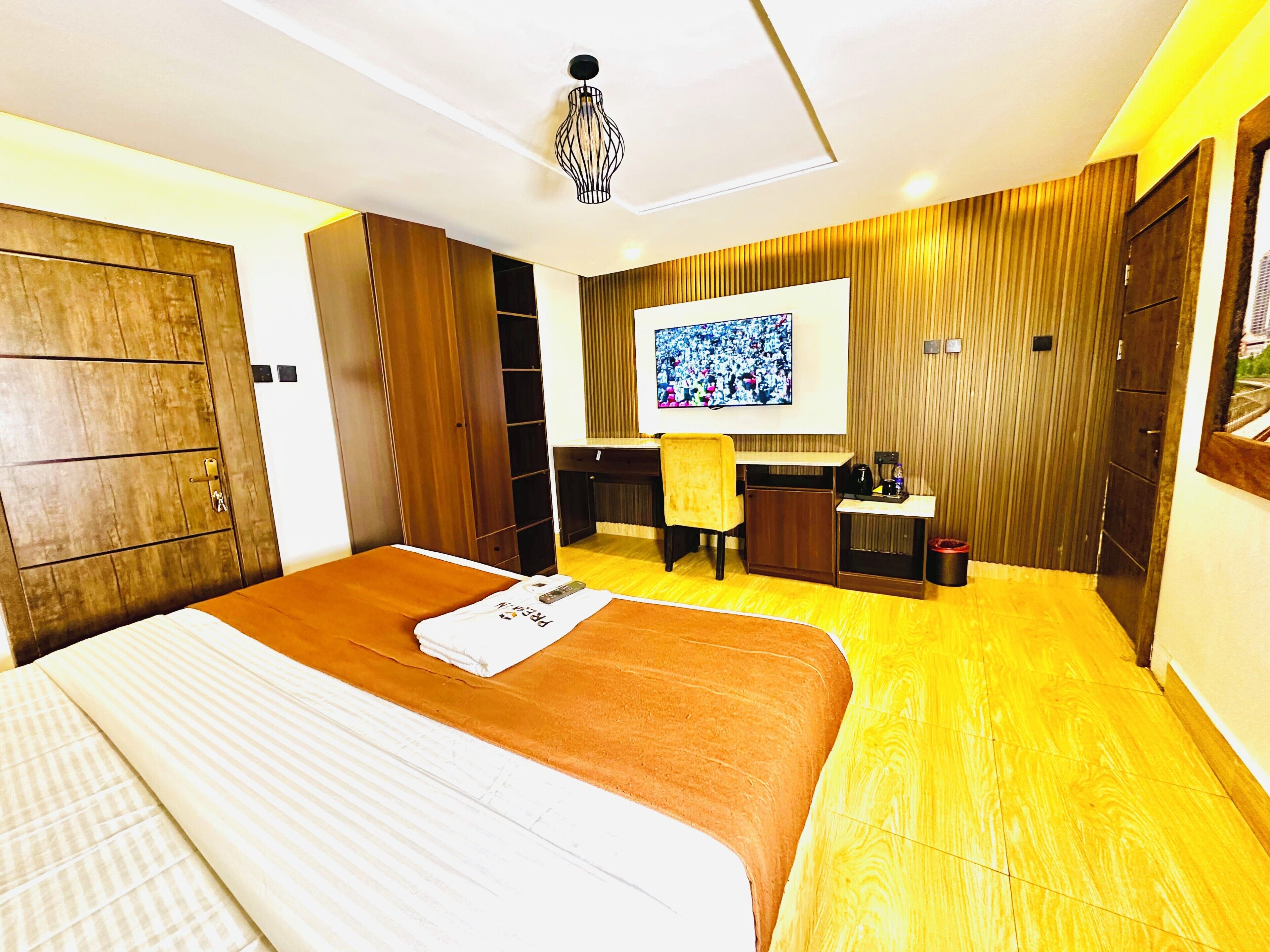 Ein Hotelzimmer mit Bett, Schreibtisch, Stuhl, Fernseher und Kleiderschrank.