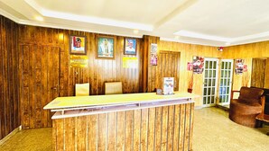 A reception area with a wooden reception desk, seating, and various informational posters on the walls. - Presken Hotel Reliance (Lagos)