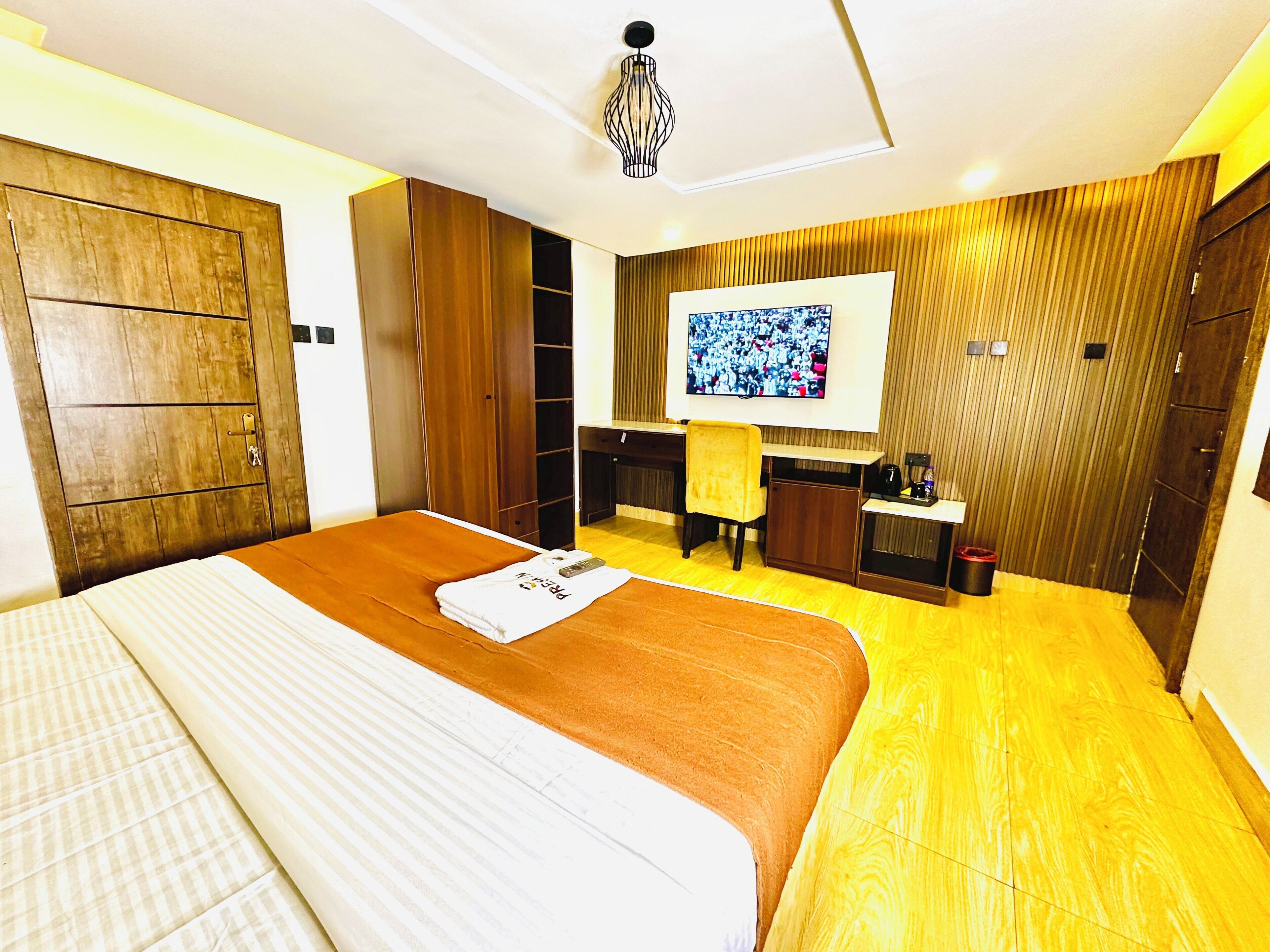 A hotel room with a bed, a desk, a television, and a wardrobe.