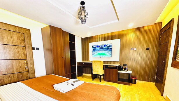 A hotel room with a large bed, a desk, a chair, and a television on the wall. - Presken Hotel Reliance (Lagos)