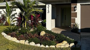 Um edifício moderno com uma placa indicando o número 313, rodeado por plantas tropicais e uma moldura de pedra.