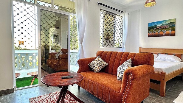 Un salon avec un canapé, un lit, un ventilateur de plafond et un tableau accroché au mur.