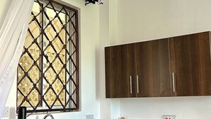 Une cuisine avec des meubles de rangement en bois foncé, un évier en acier inoxydable, une bouilloire, une cuisinière et un luminaire suspendu.