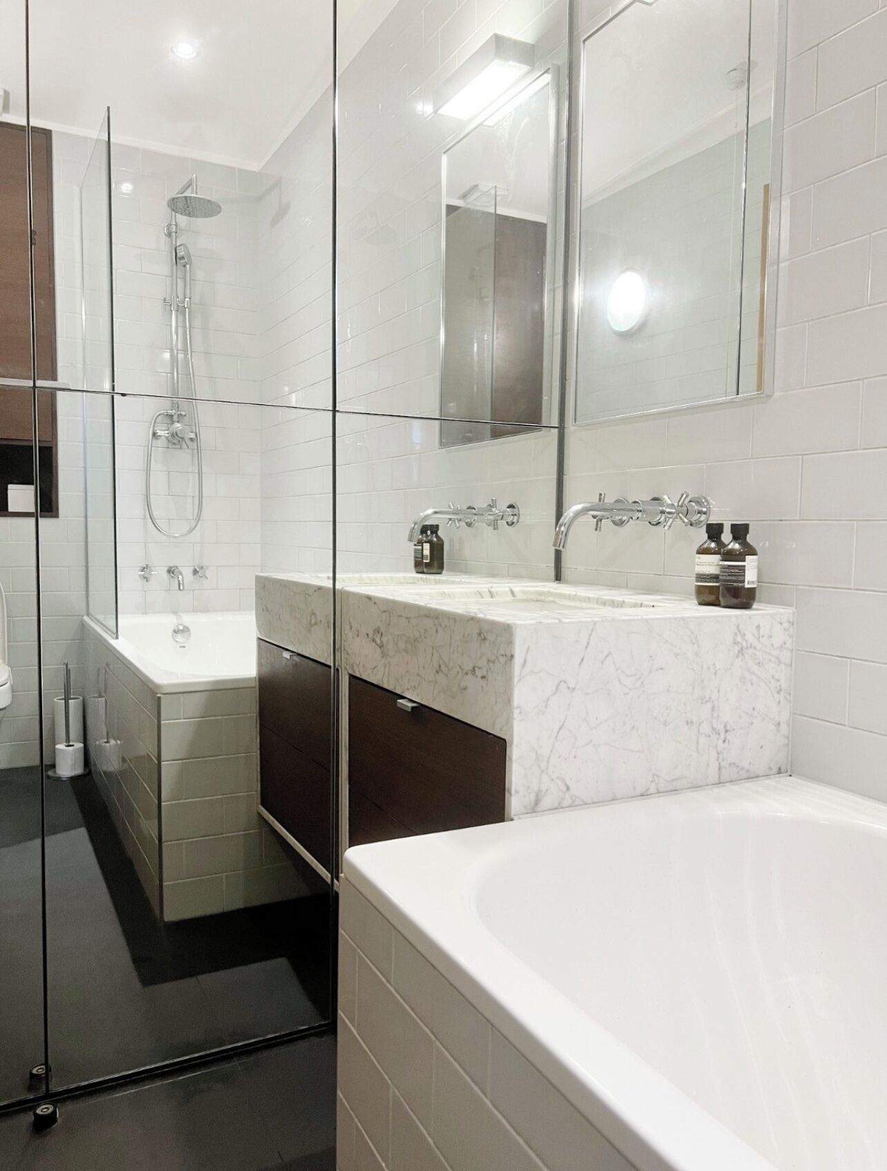 Un bagno moderno con doccia vetrata, una grande vasca e un mobile lavabo con specchio.