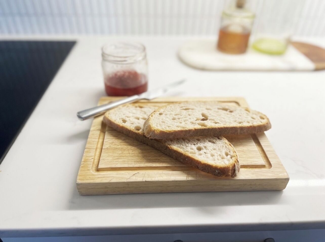 Slices of bread on a wooden cutting board on a white countertop.