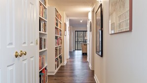 A hallway with wooden flooring, white walls, and bookshelves.