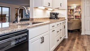 A modern kitchen with white cabinets, a granite countertop, and a dishwasher.