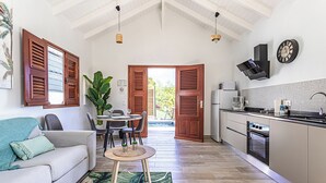 Eine moderne Küche mit integriertem Backofen, Mikrowelle und Spüle. Ein Essbereich mit Tisch und Stühlen lädt zum Verweilen ein, und eine große Pflanze bildet das Zentrum des Raumes.