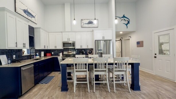 A spacious kitchen with white cabinets, a central island, and pendant lighting. - Fish Stories 5 Bedroom/3.5 Bathroom With Pool and Playscape (Port O'Connor)