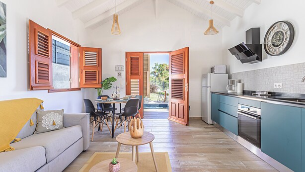A modern kitchen with teal cabinets, a stainless steel oven, and a black range hood.