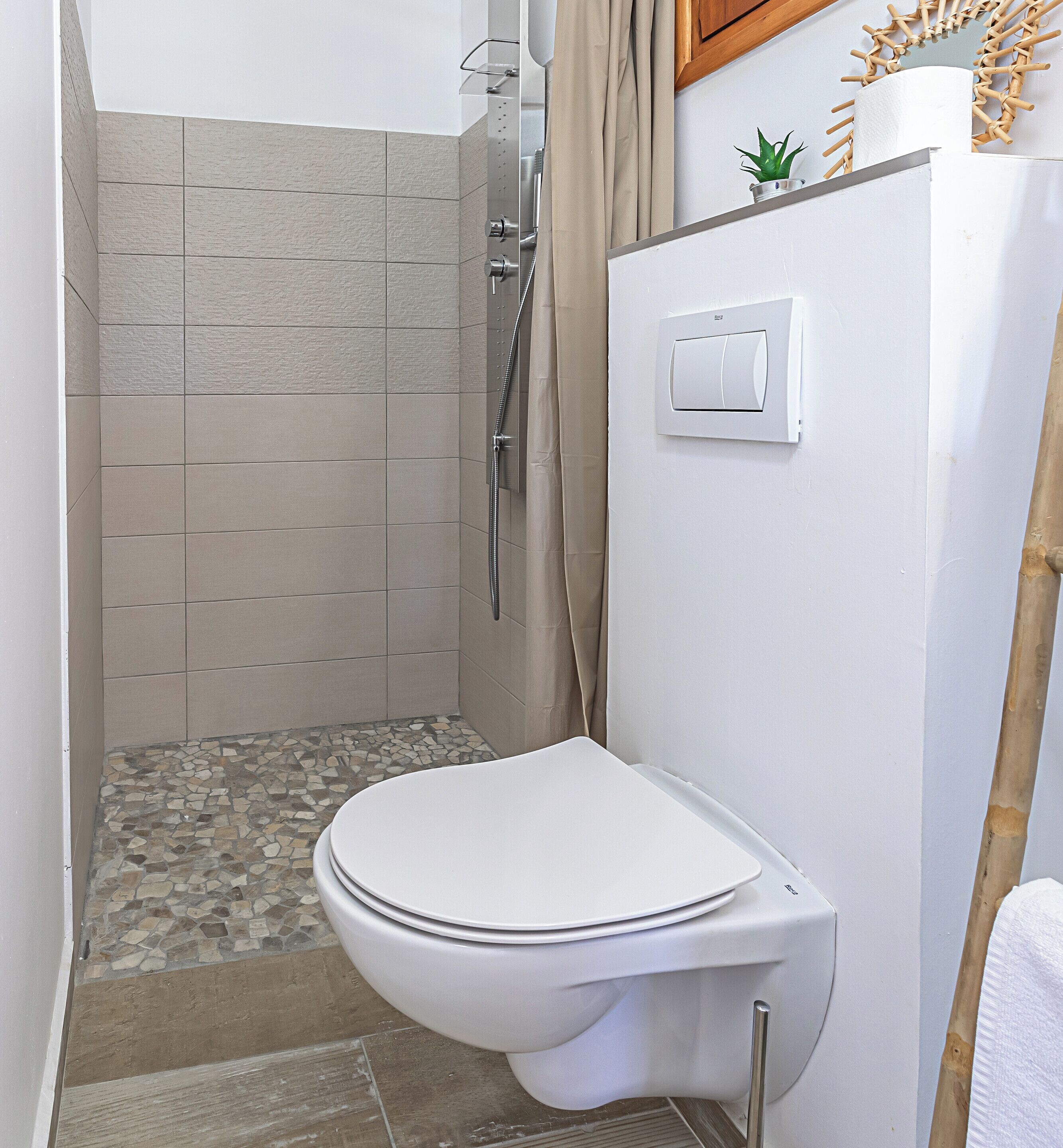 Un baño con ducha, inodoro e interruptor de luz en la pared.