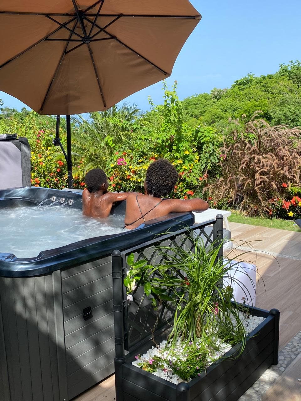 A hot tub with two people enjoying the view of a lush garden.
