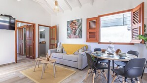 A modern living space with a dining area, a sofa, and a painting on the wall.