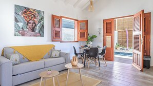 A living room with a sofa, coffee table, and dining area with chairs and a table.