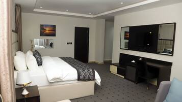 Une chambre d’hôtel moderne avec un grand lit, un bureau, une chaise, une télévision et un tableau au mur.