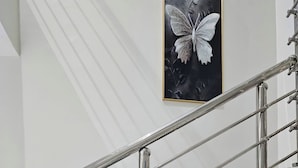 A staircase with metal railings and a framed butterfly artwork on the wall. - Anibex Luxe (Abuja)