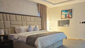 A bedroom with a large bed, a nightstand, a lamp, and a painting on the wall. - Anibex Luxe (Abuja)