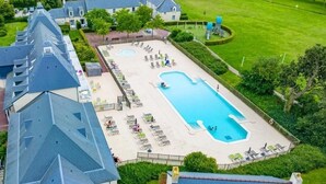 An aerial view of a hotel with a large rectangular swimming pool surrounded by lounge chairs and a grassy area. - Luxury living in the heart of Normandy (Port-en-Bessin-Huppain)