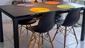 A dining area with a table, chairs, a pendant light, a lamp, and a framed picture on the wall.