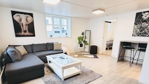 A modern living room with a sectional sofa, a glass coffee table, and a large window. - Apartment in the heart of Stavanger (Stavanger)