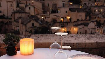 A table set for dining with a candle, plates, and cutlery, overlooking a historic cityscape with buildings and lights.