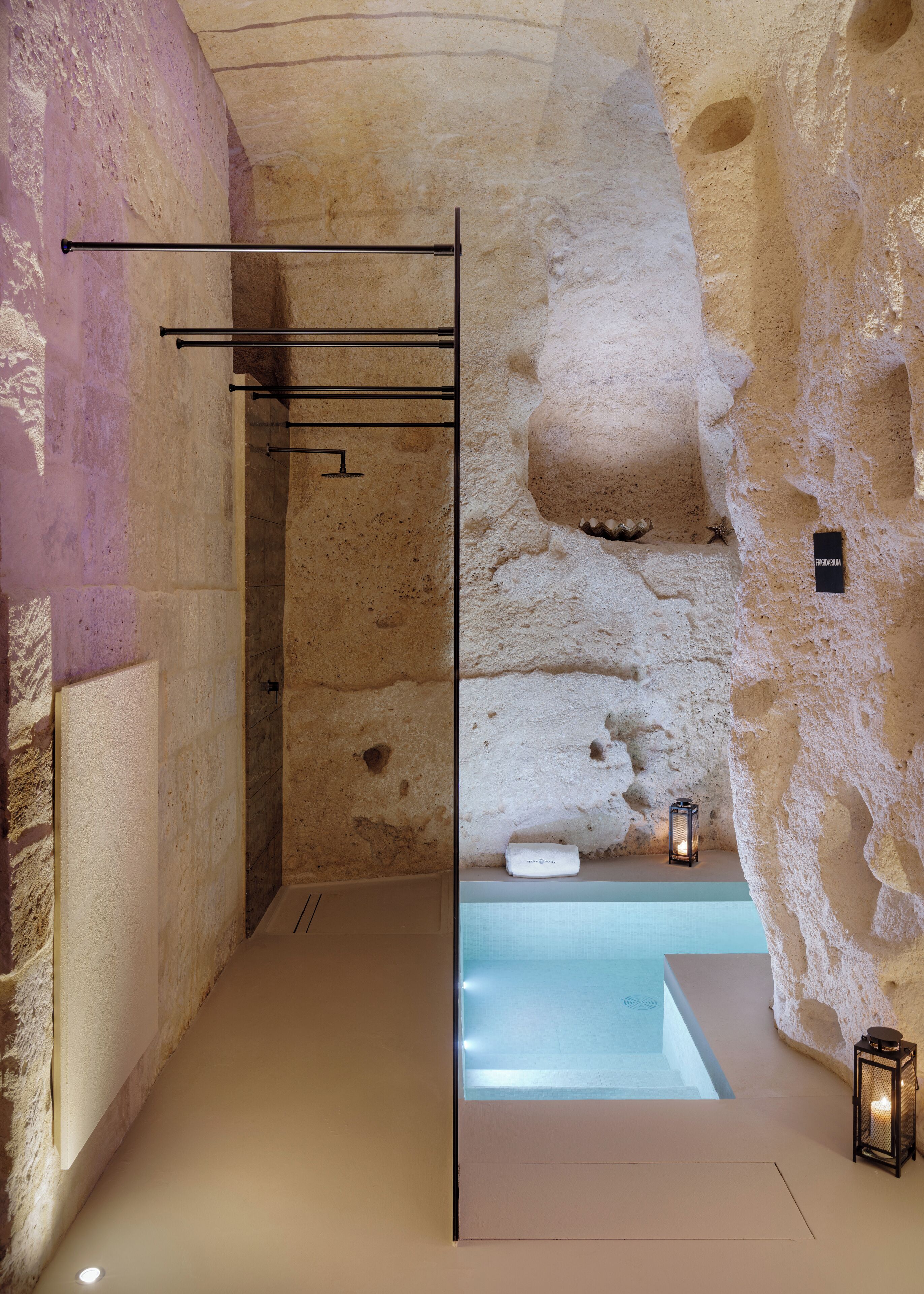 A spa room with a stone wall, a bathtub, and a small lantern.