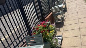 Outdoor seating with tables and chairs, surrounded by flower planters. - Student Only Apollo Court (Liverpool)