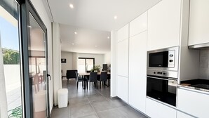 A modern kitchen with white cabinets, a built-in oven, and a microwave. - Casa da Praceta - By SCH (Alfeizerão)