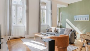 Una sala de estar moderna con un sofá, una mesa de centro y vistas de la ciudad a través de amplios ventanales.