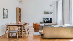 Una sala de estar moderna con una mesa de comedor de madera, sillas, un sofá y un televisor.