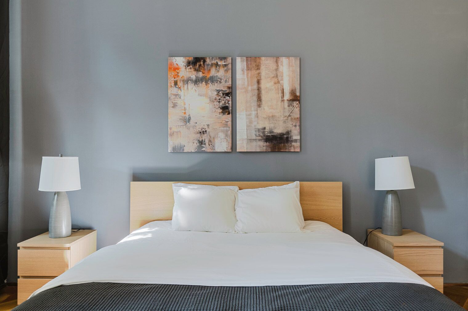 Une chambre d’hôtel avec un grand lit, deux tables de chevet et une œuvre d’art abstraite au mur.