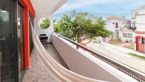 A balcony with a view of a street, a round mirror, and a small table with chairs. - Beach Apartment#3 2BDR 1BTH in Villas Playa Blanca (Cancún)