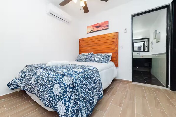 A bedroom with a bed, wooden headboard, and a painting on the wall. - Beach Apartment#3 2BDR 1BTH in Villas Playa Blanca (Cancún)