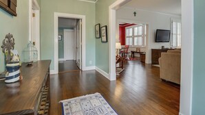Un salon spacieux doté de parquet, d’un lustre et d’un coin repas avec une table et des chaises en bois.