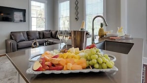 A kitchen with a fruit platter, a bottle of champagne, and a pineapple on the counter.