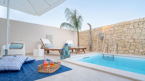 Ein Poolbereich mit Liegestühlen, einem kleinen Pool und einer Steinmauer.