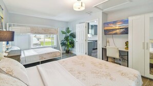 A bedroom with two beds, a desk, a chair, a potted plant, and a painting. - Tropical Oasis •Pet-Friendly + Pool Clearwater (Largo)
